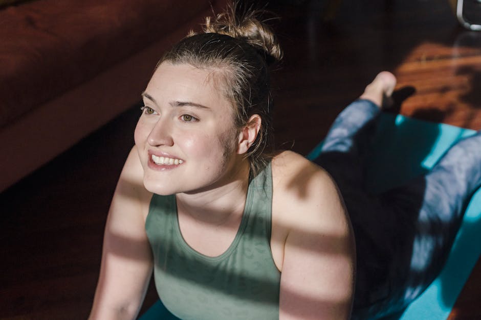 Woman in a comfortable yoga pose smiling gently in a sunlit room